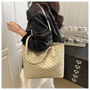 Detail of a large cream tote bag with M-pattern print and long shoulder straps