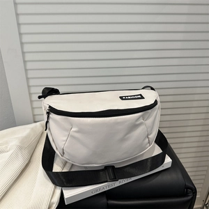 Minimalist off-white crescent crossbody bag with adjustable black strap and fashion label