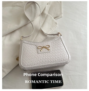 Detail view of woven texture and golden bow buckle on the beige underarm baguette bag