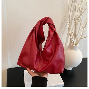 Close-up of a stylish red knot handbag with a smooth faux leather finish and modern design