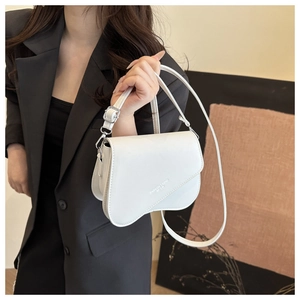 Close-up of white crossbody saddle bag with Fashion Trend print on black blazer