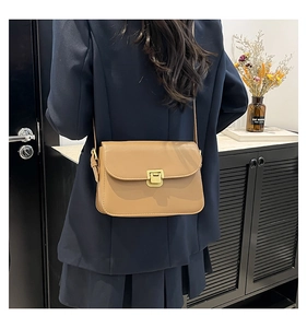 Sac à bandoulière classique en cuir kaki avec boucle dorée sur un blazer marine