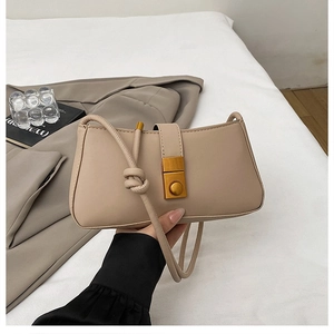 Detail of beige shoulder bag with vintage gold clasp and elegant knot on the strap