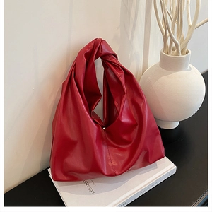 Close-up of the red pleated bucket bag with a large decorative knotted handle design