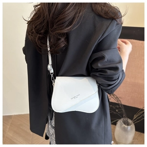Détail du sac à main blanc brillant avec rabat ondulé et texte Fashion Trend sur un blazer