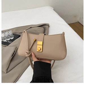 Detail of nude baguette bag with a gold square clasp and elegant knot handle detail