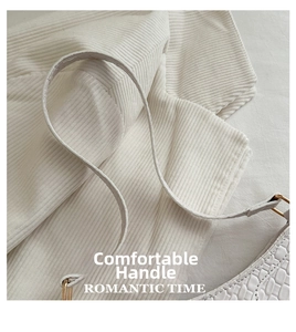 Detail view of the comfortable leather handle and white crocodile embossed texture on bag