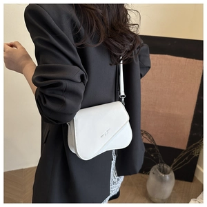 Détail du sac besace blanc avec boucles argentées porté sur un blazer noir