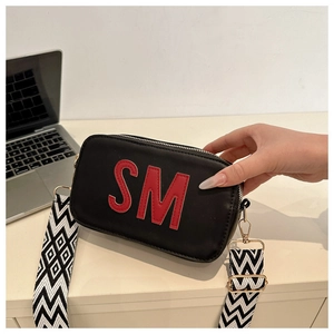 Détail du sac à bandoulière en cuir noir avec logo SM et sangle tissée bicolore