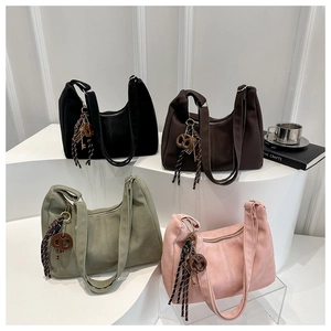 Detailed view of suede-textured tote bags in four colors with decorative tassels and knots