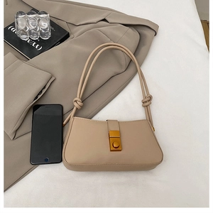 Detail of beige faux leather baguette bag with gold twist lock and knot strap detail