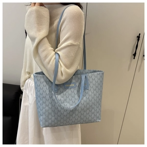 Detailed close-up of light blue tote bag with M-pattern print and gold fashion label