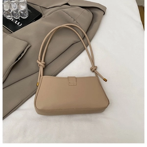 Detail of beige shoulder bag showing knot strap design and premium leather texture