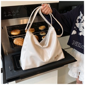 Detail of white glossy hobo bag with metal logo plate in a lifestyle kitchen setting