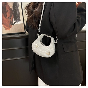 Mini sac croissant argenté avec boucles papillon porté par un mannequin de profil