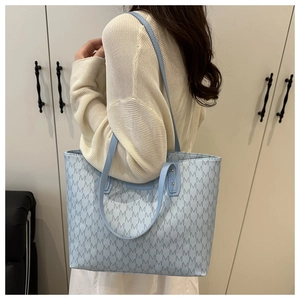 Blue tote bag with navy M-letter pattern shown on a model for casual daily use