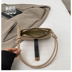 Detail view of beige shoulder bag interior featuring a zipper pocket and gold satin lining
