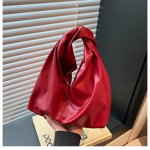 Detail of red PU leather bucket bag featuring a unique knotted handle and pleated design