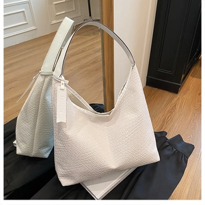 Macro shot of white woven texture hobo bag with a leather fashion tag on a wood floor