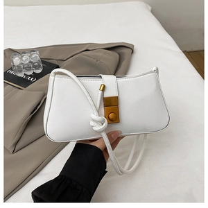 Detail of white baguette bag featuring gold rectangular lock and knotted rope strap