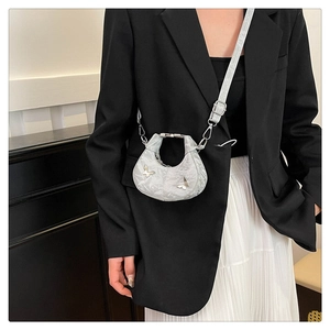 Sac croissant argenté avec breloque papillon porté par un mannequin en tenue