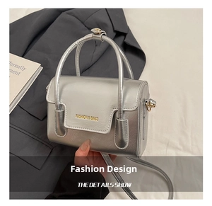 Détail du mini sac argenté métallisé avec lettrage embossé et bandoulière amovible