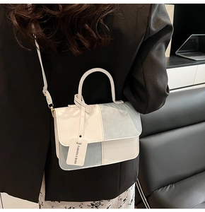 Detail of blue and white patchwork leather crossbody bag with top handle and strap