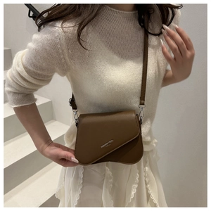 Detailed view of coffee leather saddle bag with silver Fashion Trend logo on flap
