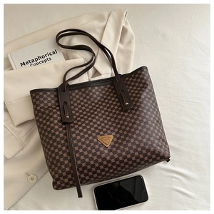 Vue détaillée d'un sac cabas marron foncé texturé avec logo triangulaire doré et bretelles