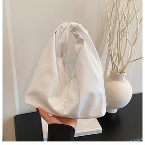 Detailed close-up of white pleated bucket bag with unique twisted handle and soft texture