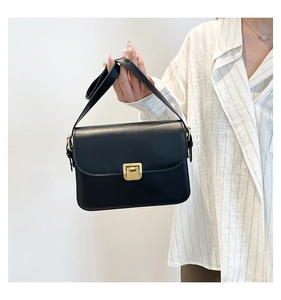 Gros plan d'un sac bandoulière noir mat avec un fermoir en métal doré rectangulaire chic