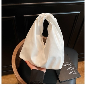 Detailed view of a white PU leather hobo bag featuring a unique knotted top handle design
