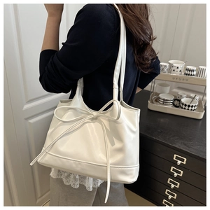 Close-up of a white PU leather tote bag featuring a large decorative bow and shoulder straps