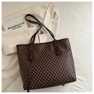 Détails du motif vintage et des poignées en cuir sur un sac cabas marron foncé