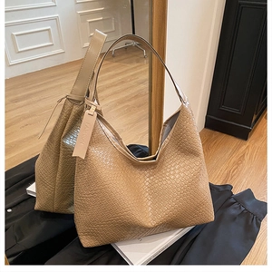 Detailed view of brown woven tote bag featuring a leather fashion tag and wide strap