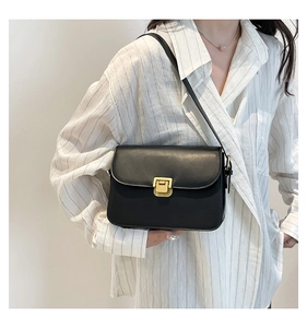 Détail d'un sac bandoulière vintage en cuir noir avec une boucle dorée sur un modèle