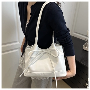 Détail du cabas en similicuir blanc avec un grand nœud décoratif et une texture lisse