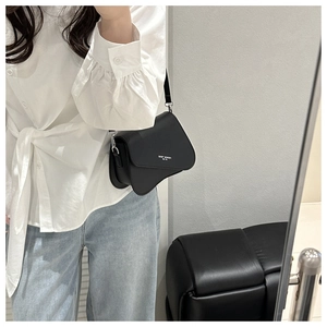 Selfie miroir montrant un sac besace noir avec rabat ondulé et bandoulière réglable