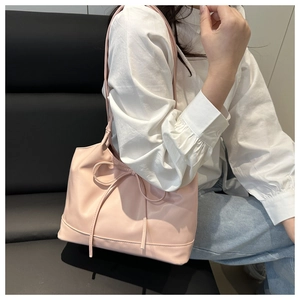 Detail of pink shoulder bag featuring a decorative bow knot and soft leather texture