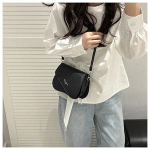 Detail of a black square crossbody bag with asymmetric flap and white logo lettering