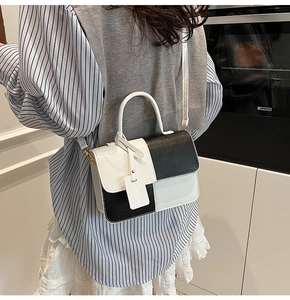 Vertical view of black and white leather crossbody bag worn by a model in lifestyle setting