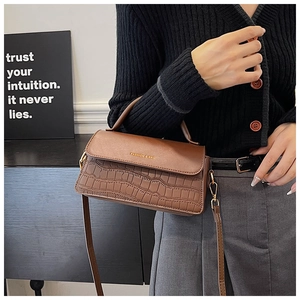 Detail of brown faux leather bag with crocodile texture and gold hardware accents