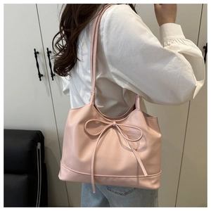 Detailed view of a sweet pink PU leather tote bag with a decorative bow and long shoulder strap