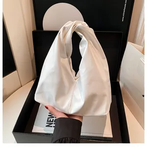 Makro-Detail der weißen Falten-Eimertasche mit gedrehtem Griff und weicher Ledertextur