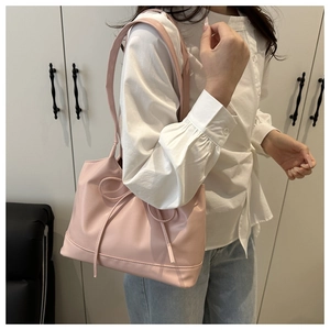 Vue détaillée du sac rose montrant le grain du similicuir et le nœud décoratif