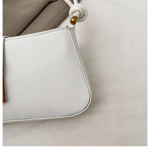 Close-up of white PU leather shoulder bag featuring hand-knotted strap and gold metal accents