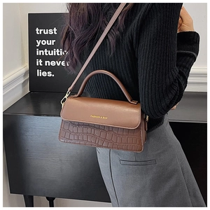 Brown faux leather crossbody bag with crocodile pattern and adjustable strap on model