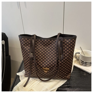 Détail d'un sac cabas à carreaux marron avec logo triangle doré et lanières en cuir