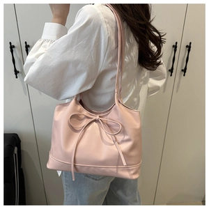 Détail du sac cabas en cuir ciré rose avec grand nœud porté par un mannequin