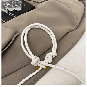 Close-up of a white leather knotted shoulder strap with premium gold metal tips